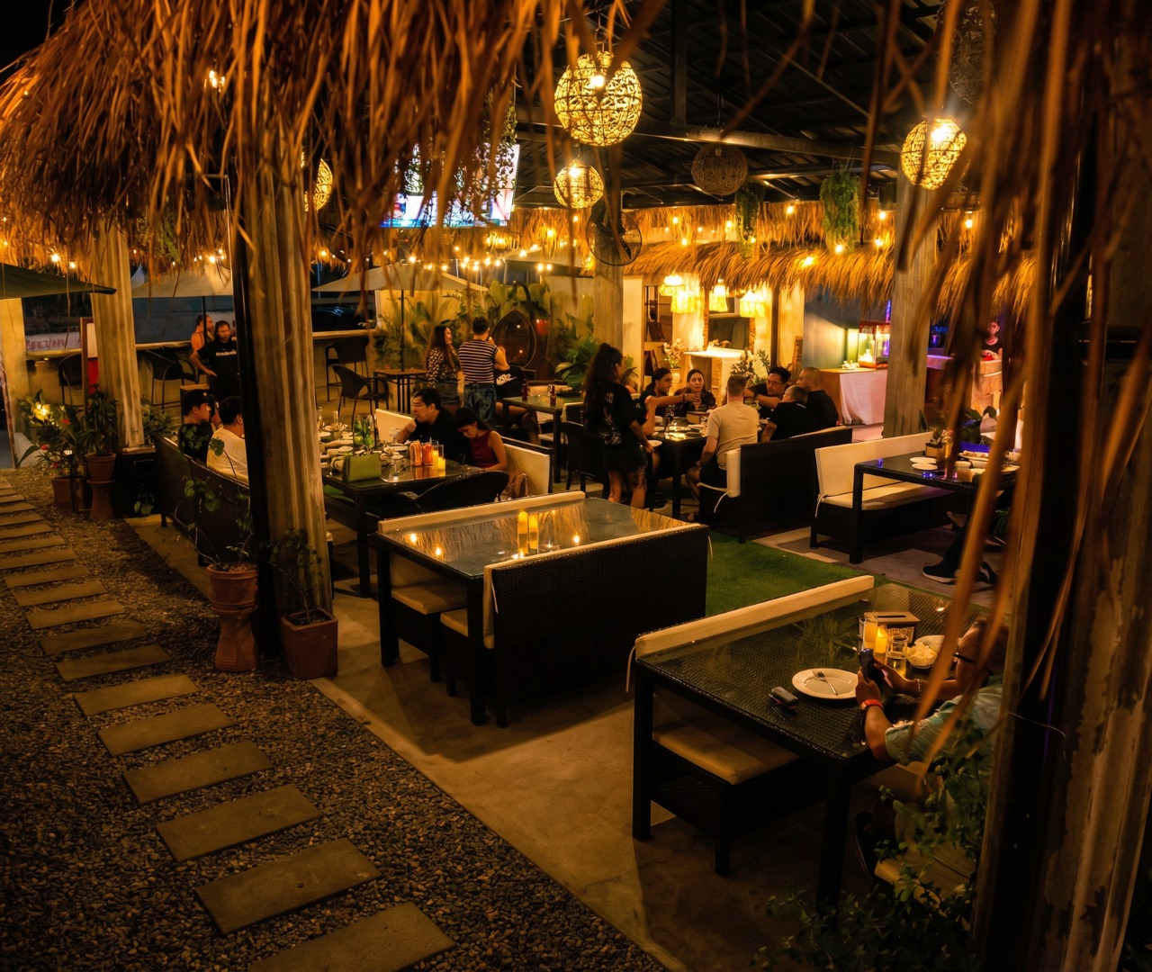Guests dining in Hardin's garden al-fresco area at night under festoon lights